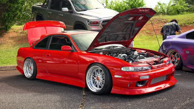 Red Nissan 240SX (S14) slammed with the hood up at a meet.