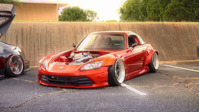 Slammed orange Honda S2000 widebody at golden hour.